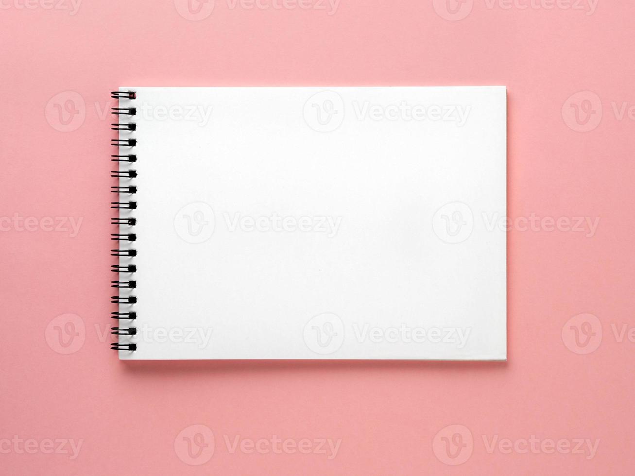 Blank notepad white page on pink desk, color background. Top view, flat lay. photo