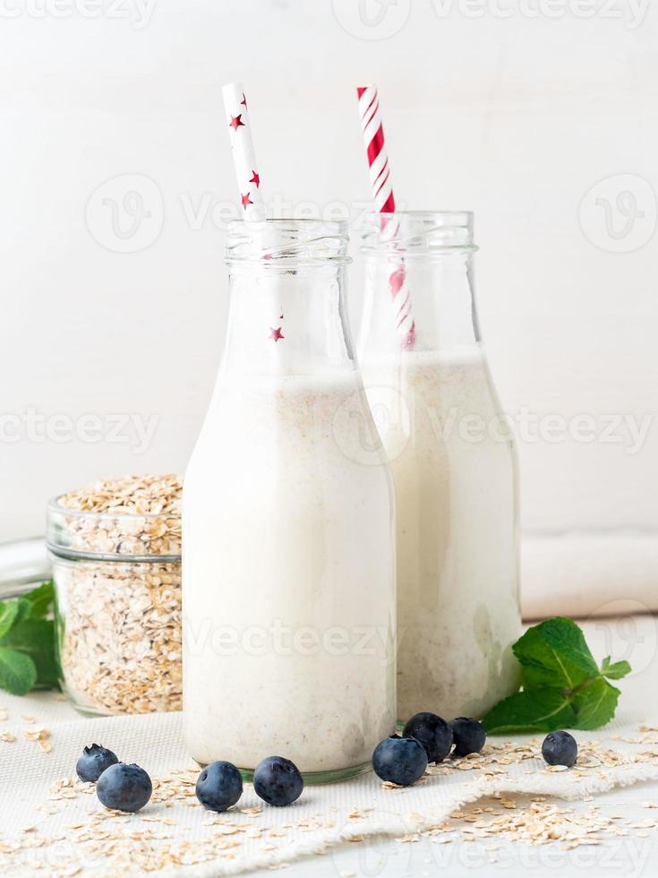 batido con avena, menta para un desayuno saludable. leche de avena en botella de vidrio con tubo sobre fondo blanco, enfoque selectivo. foto