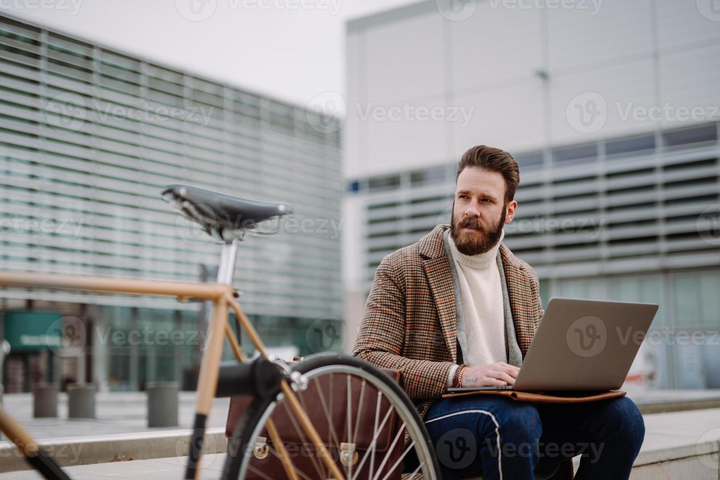 director creativo sentado en el área del centro de negocios con computadora portátil y móvil. trabajando afuera foto