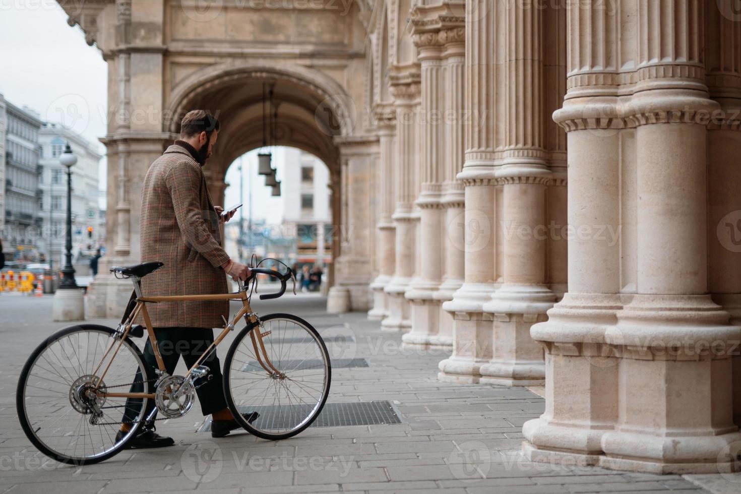 Young man holding smartphone and walking with bicycle. Eco friendly transport. photo