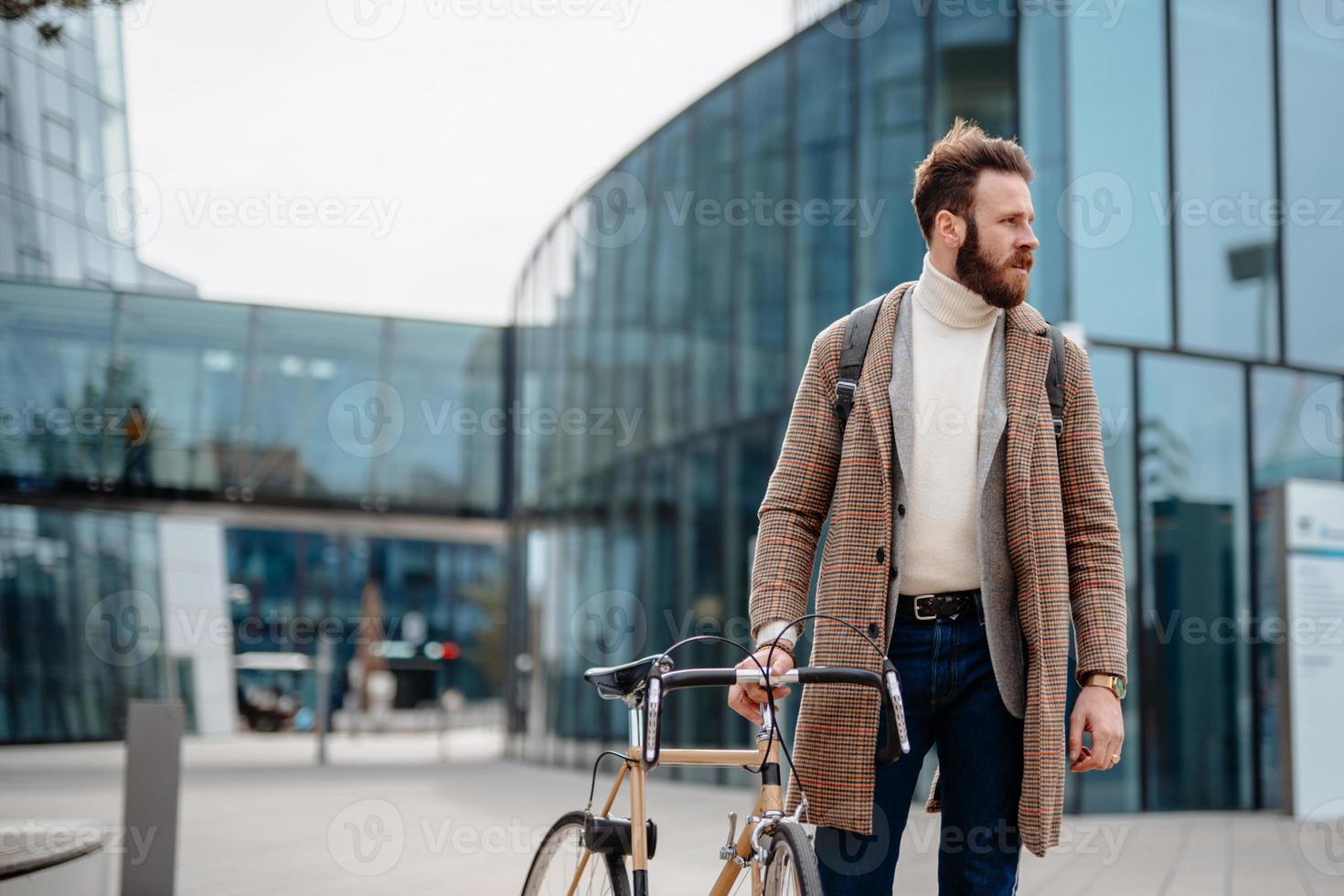 retrato de un hombre de negocios hipster con bicicleta, usando un teléfono inteligente. ubicación del centro de negocios. yendo del trabajo foto