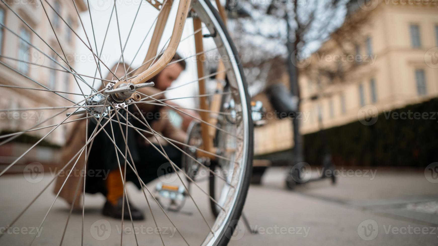 Man checking wheels on bike. Repairing bicycle at street. Background, copyspace photo