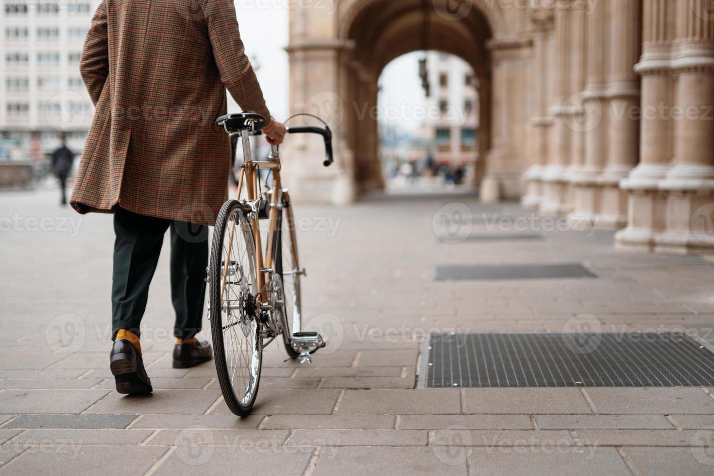 sección media primer plano de la pierna de un hombre de negocios con bicicleta yendo a la oficina. zona historica de la ciudad foto