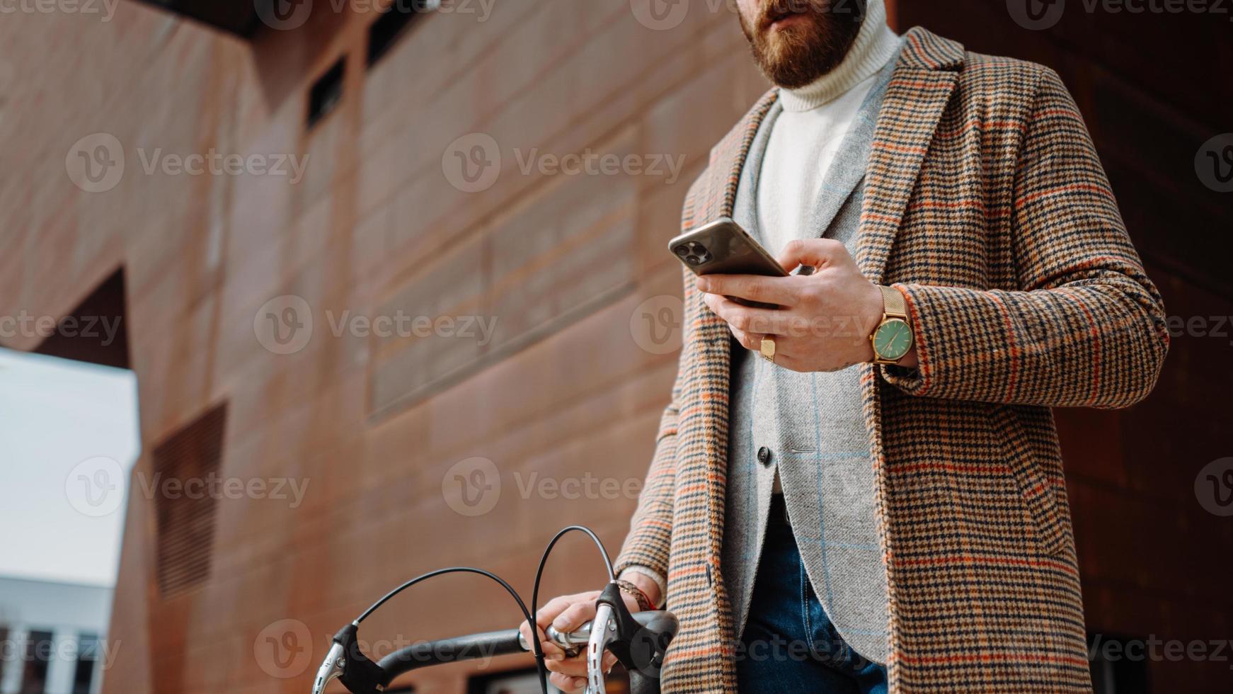 Midsection Detail of hand with phone. Businessman holding mobile phone. On the way to work with bicycle photo