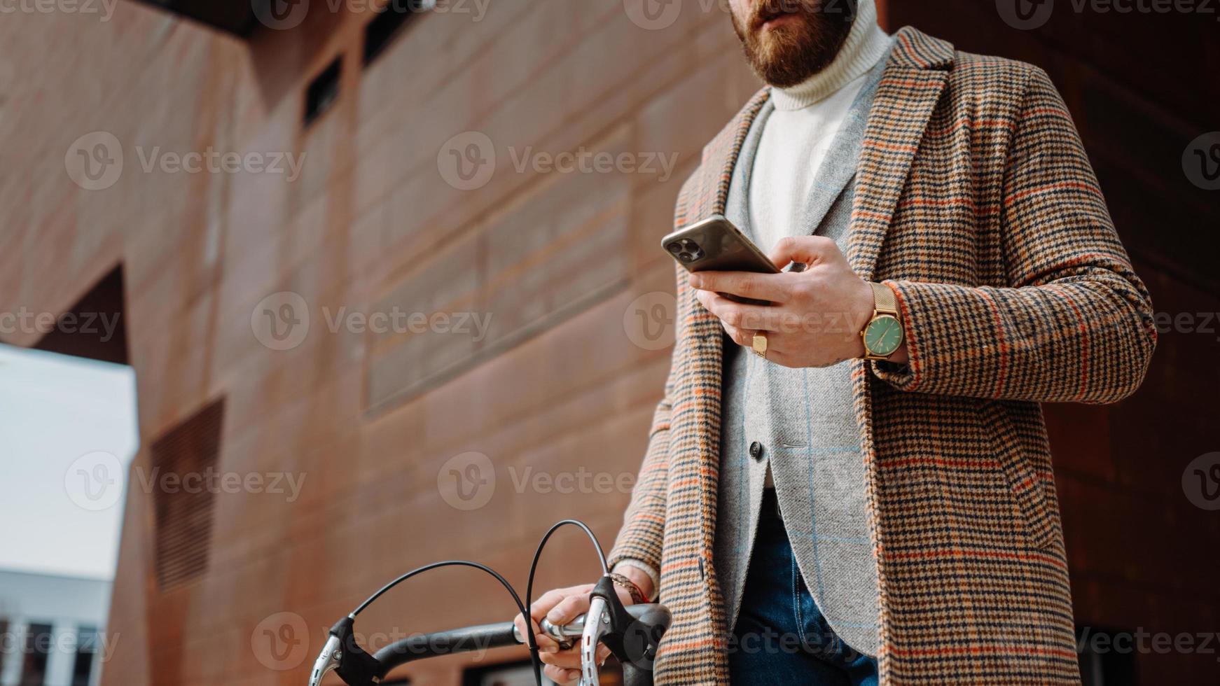 detalle de la sección media de la mano con el teléfono. hombre de negocios con teléfono móvil. en el camino al trabajo con bicicleta foto