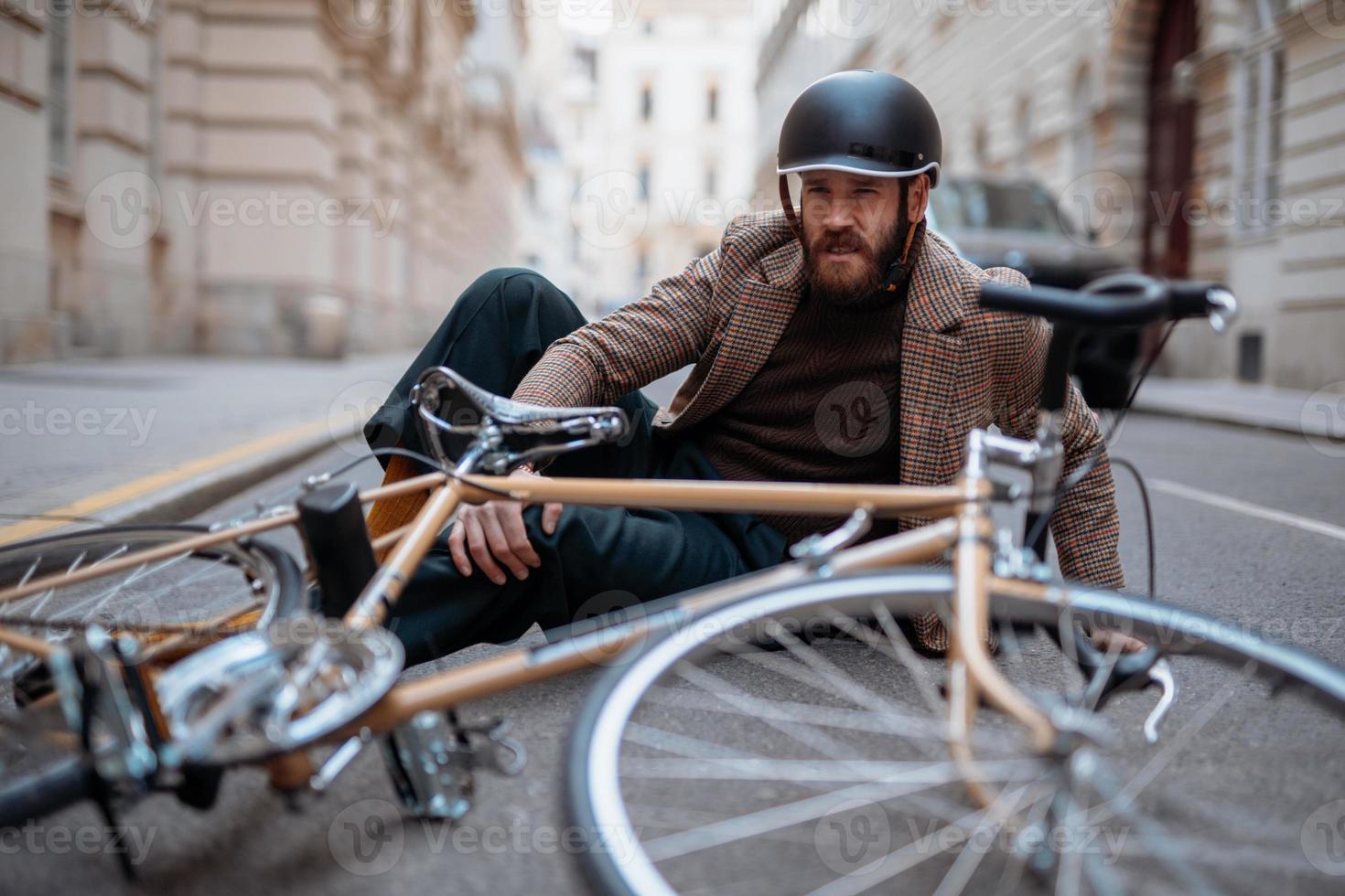 accidente de bicicleta en la ciudad. hombre ciclista se cayó de la bicicleta de carretera mientras andaba en bicicleta. lesión en bicicleta, rodilla lesionada foto