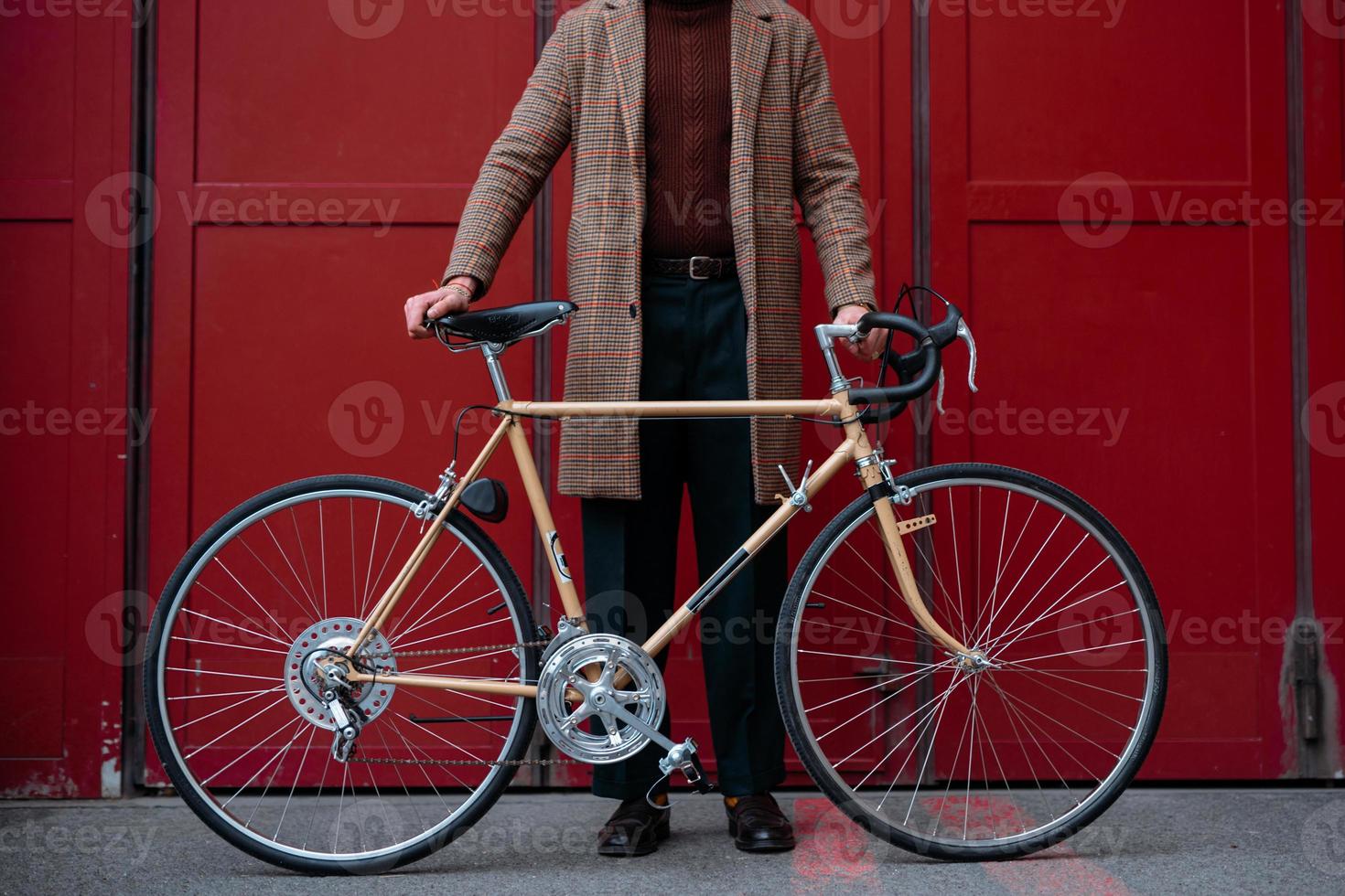 joven empresario con bicicleta sobre fondo de pared roja en una ciudad. fondo de color rojo foto