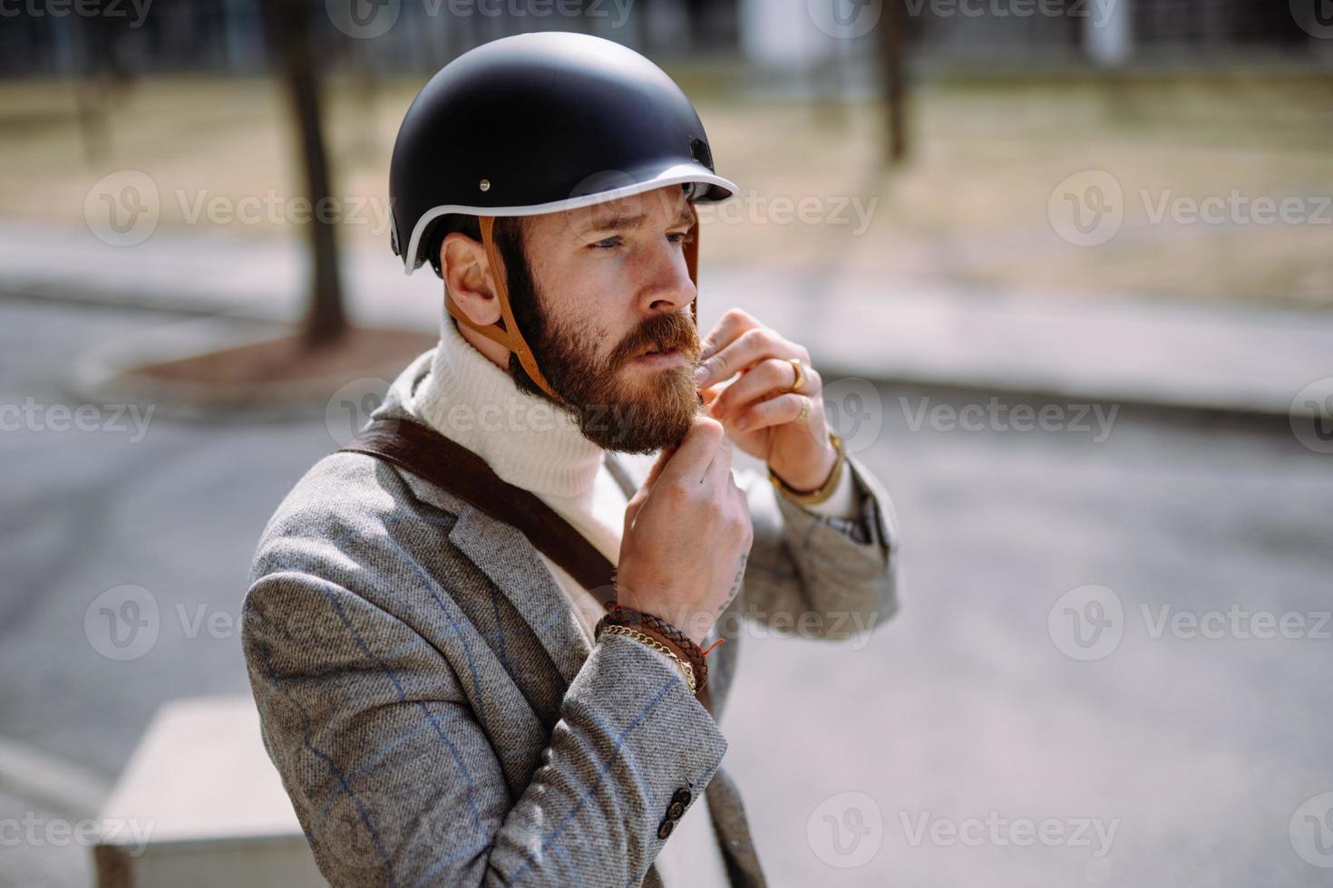 un hombre apuesto se pone el casco antes de andar en bicicleta. seguridad y transporte ecologico foto