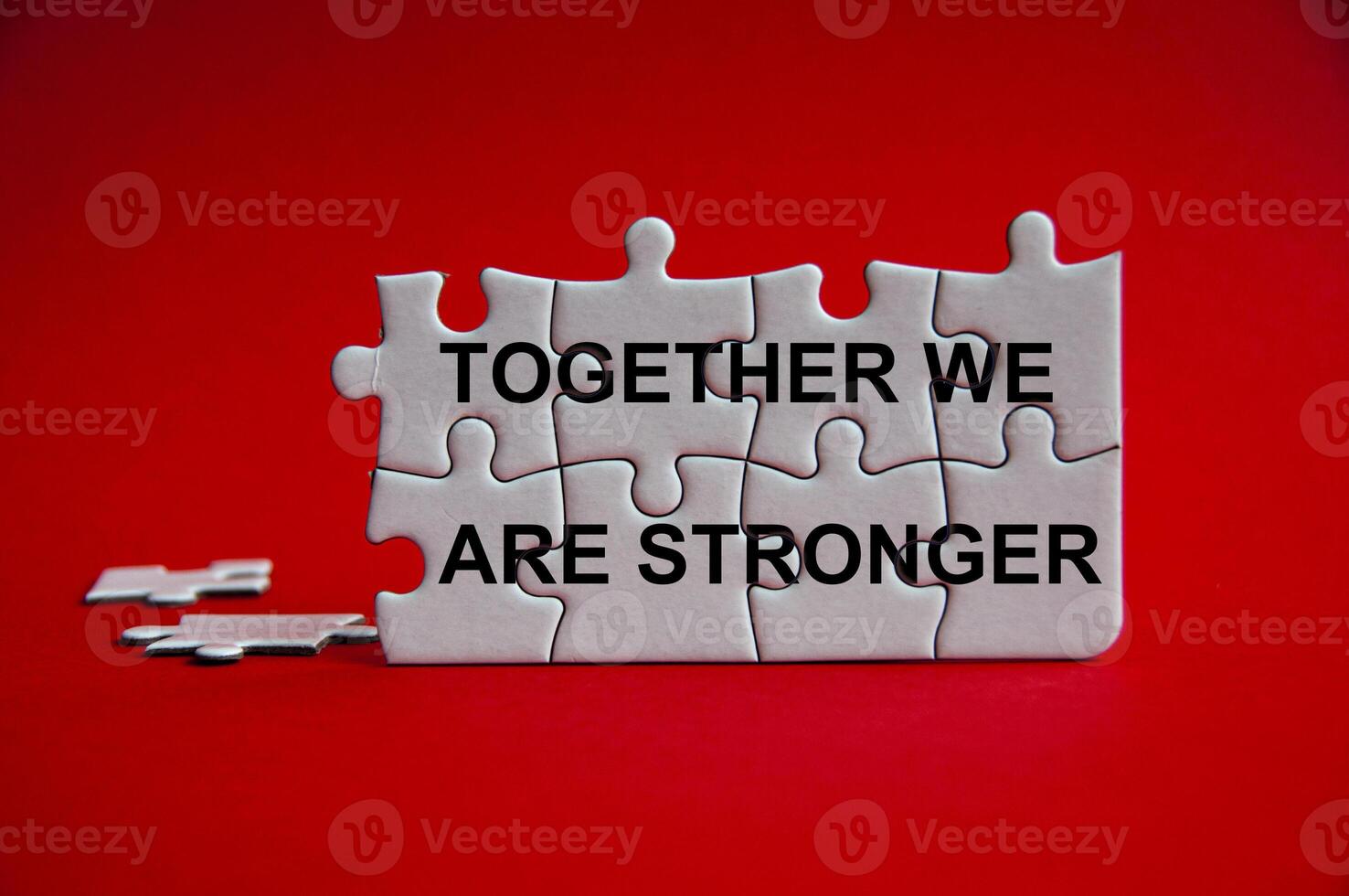 Together we are stronger text on jigsaw puzzle with red background. photo