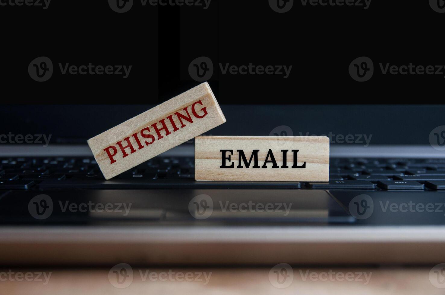 Phishing email text on wooden blocks on top of a laptop. Online business concept photo