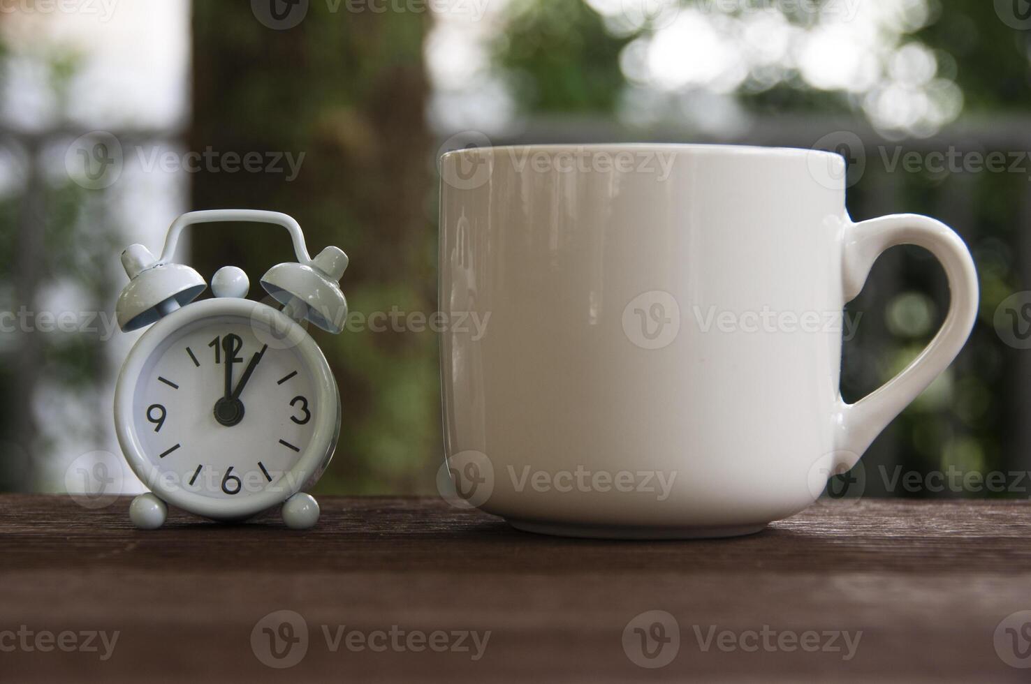 Alarm clock pointing at 1 o'clock with coffee cup on a bench. Copy space concept photo