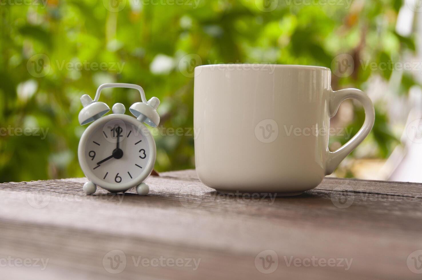 Alarm clock pointing at 8 o'clock with coffee cup on a bench. Copy space concept photo