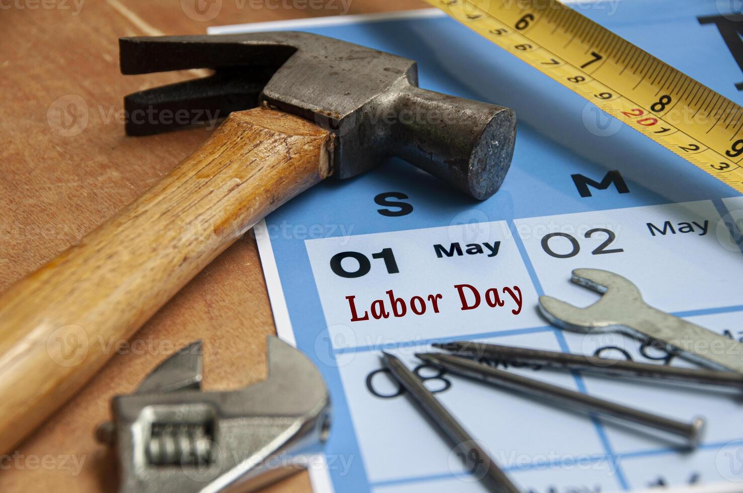 Side view of Labor Day text on torn paper with calendar and working tools background. Labor day concept. photo
