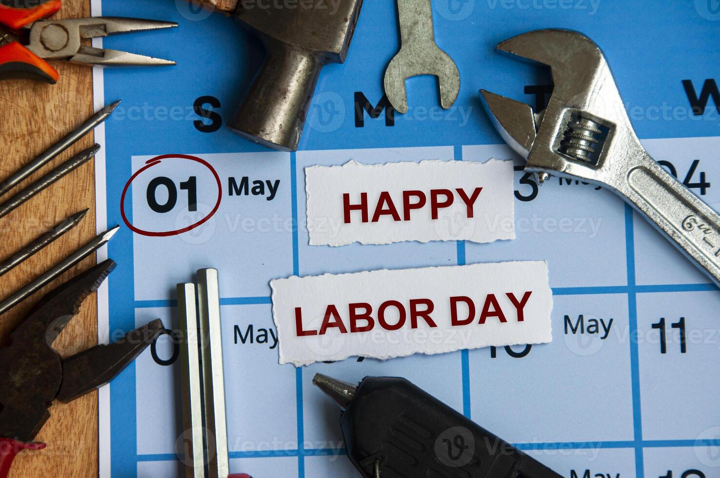 Top view of Happy Labor Day text on torn paper with calendar and working tools background. Labor day concept. photo