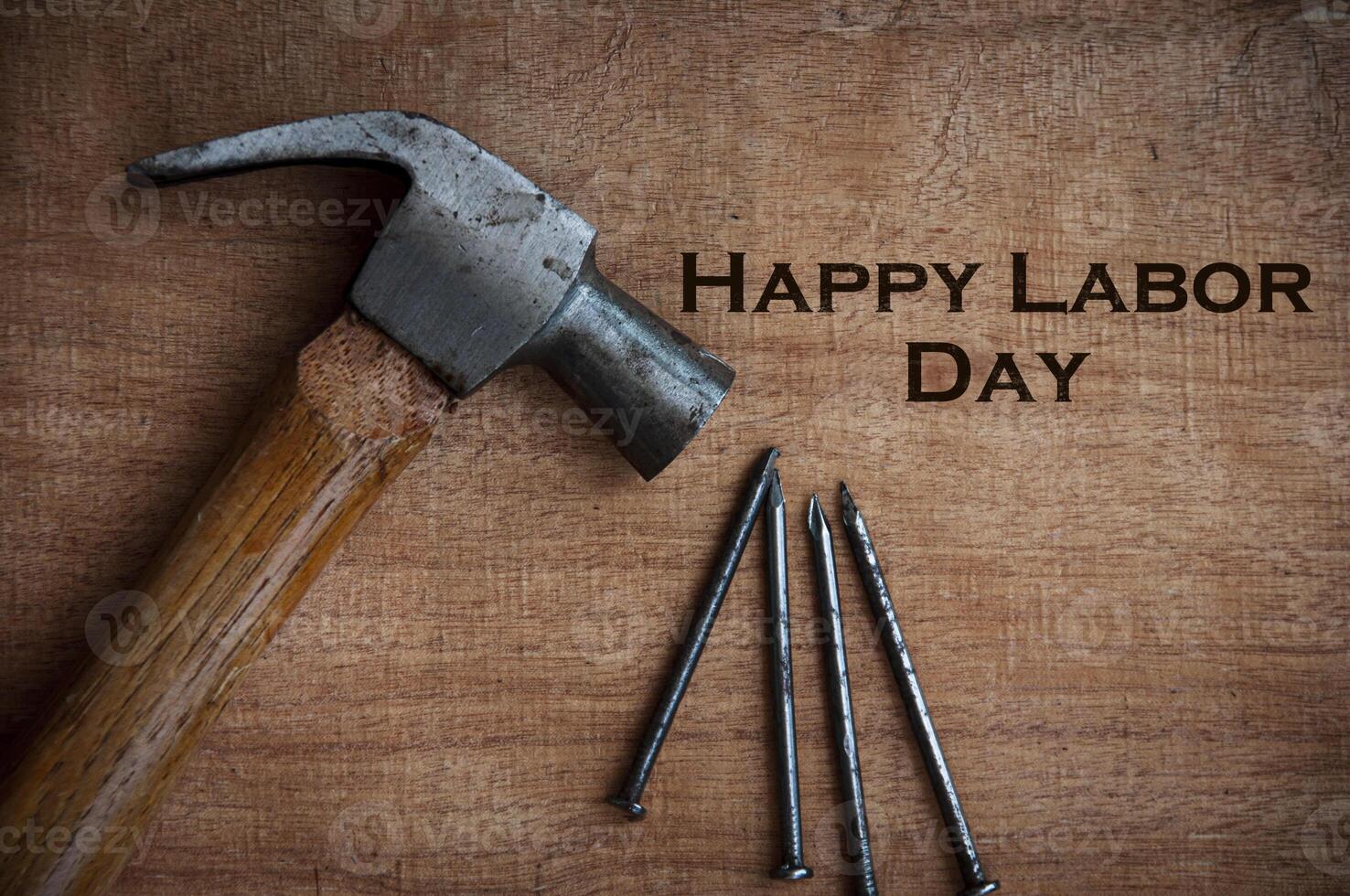 Top view of text on wooden desk - Happy Labor Day with hammer and nails background. photo