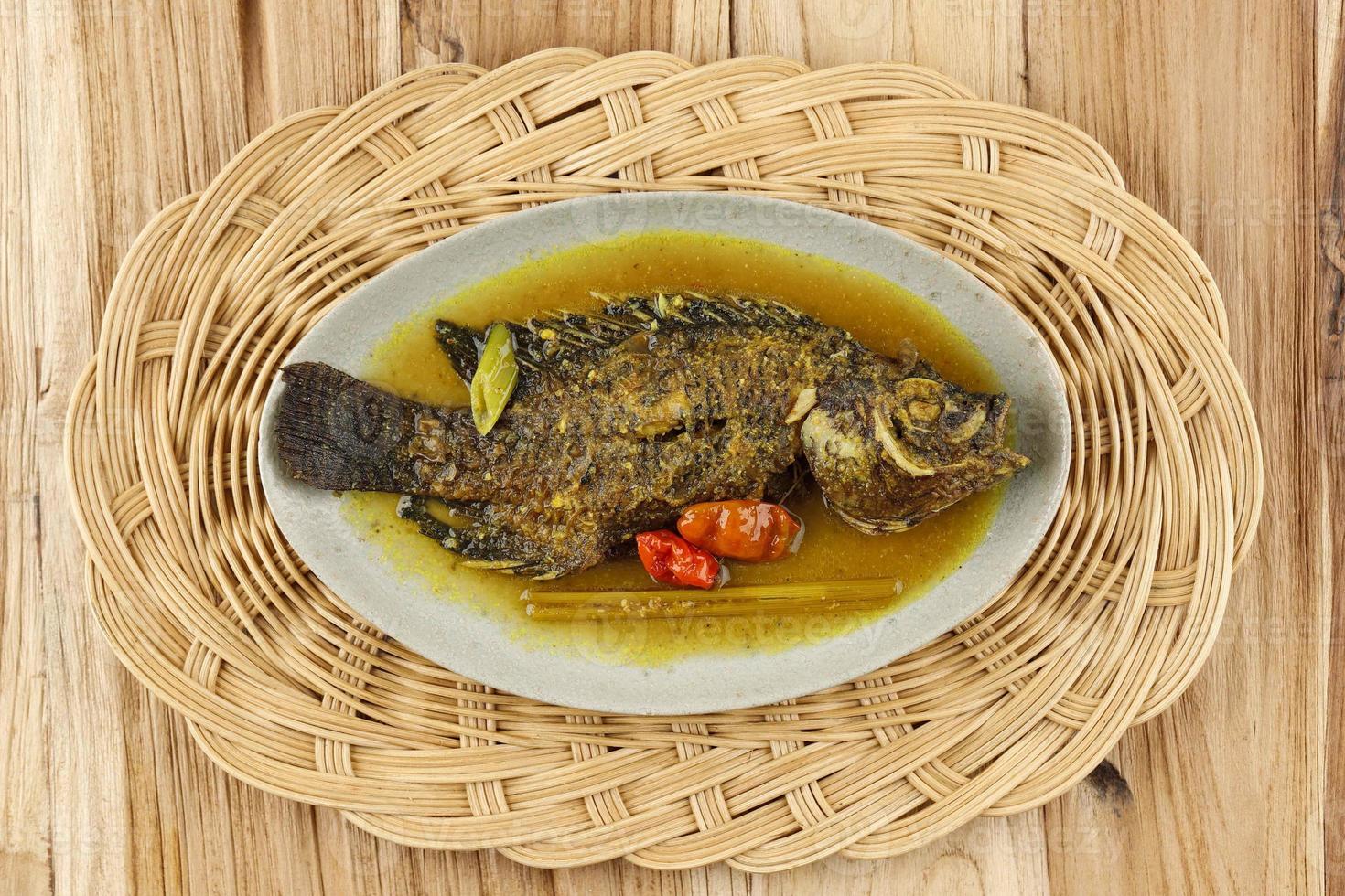 pesmol ika nila, tilapia curry amarillo, popular receta de curry hecha de pescado frito en java occidental, indonesia. foto