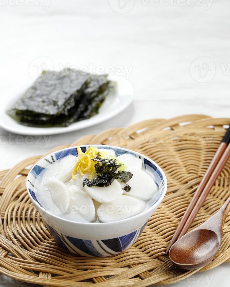 Sopa de barra de pastel de arroz coreano tteokguk para el año nuevo seollal, cubierta con rebanada de huevo, chile y semillas de sésamo foto