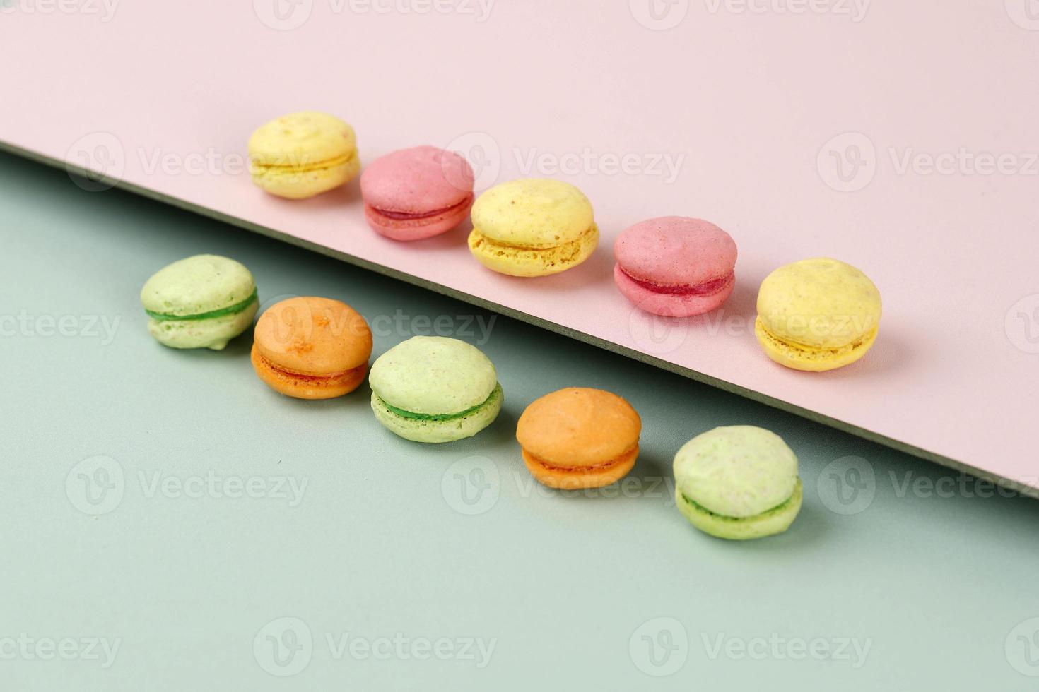 Creative layout made of colorful macaroons on the mint and pink background photo
