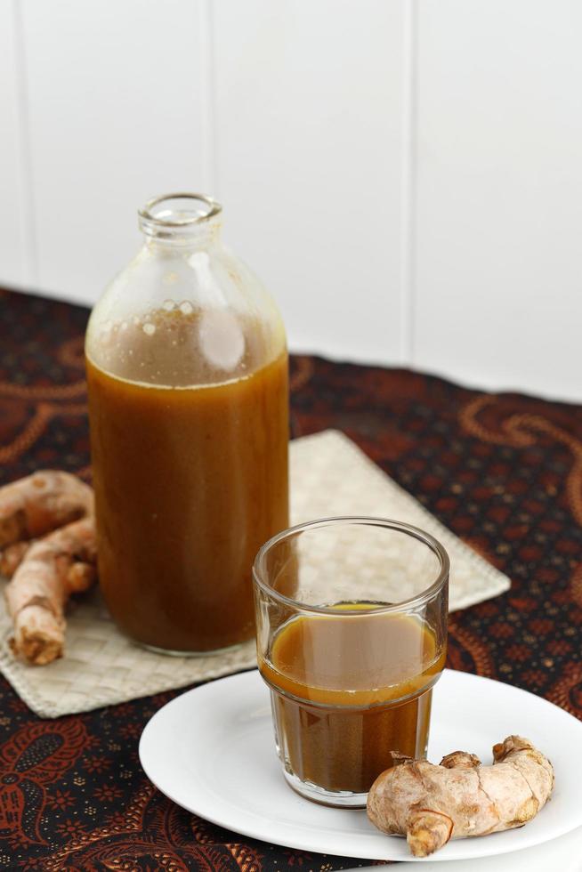 jamu kunir asem o kunyit asam es una bebida herbal tradicional indonesia hecha de cúrcuma, tamarindo y azúcar de palma. foto