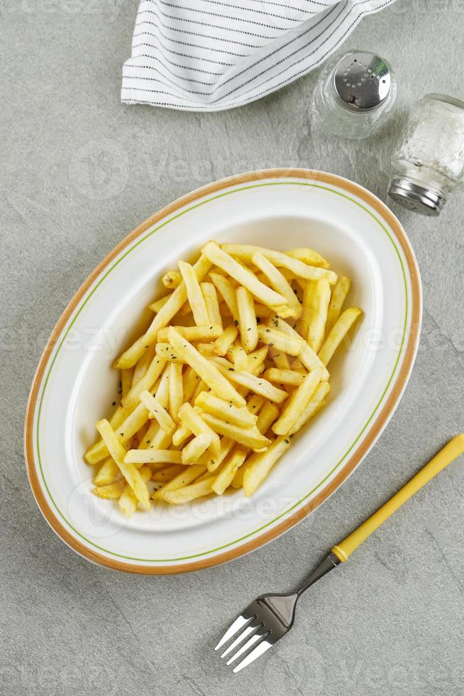 French Fries in a Bowl on a Cement Table Background, Top View photo