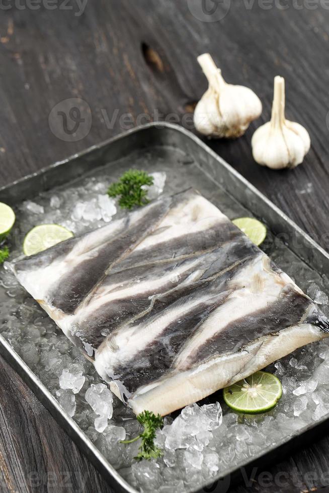 filete de bagre congelado en bandeja con rodajas de limón y hielo picado foto