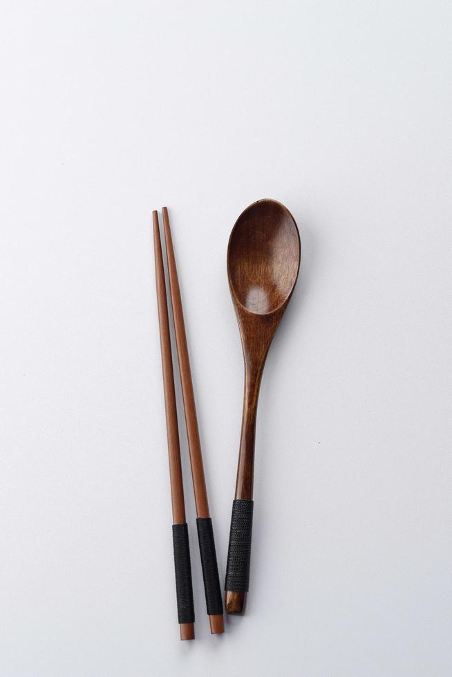 cubiertos de madera con cuchara y palillos sobre una mesa rústica de madera negra, espacio para copiar, concepto de comer foto