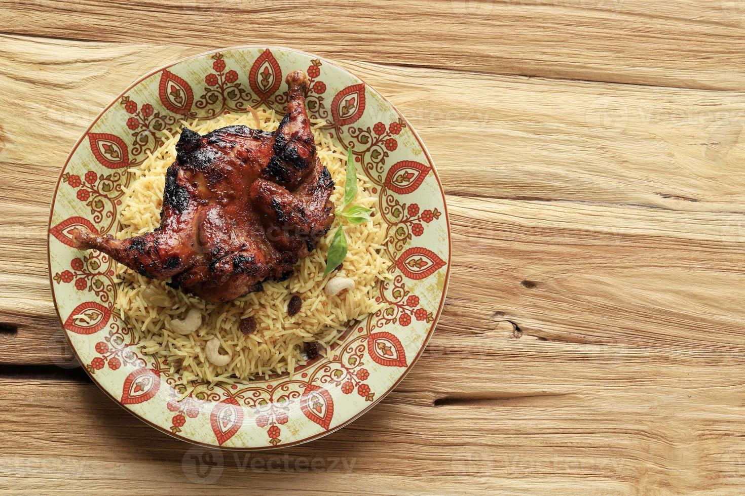 arroz kebuli nasi kabli o briyani sobre fondo crema, cubierto con pollo asado y pasas. foto