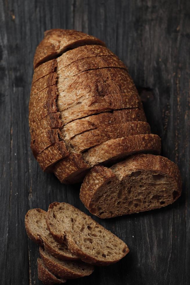 pan de masa fermentada en rodajas sobre una mesa rústica de madera foto