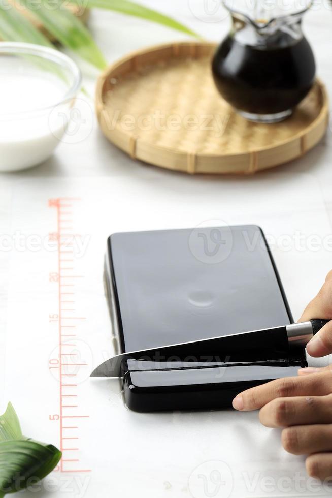 Female Homemaker Cut Cincau Hitam or Black Grass Jelly Pudding into Pieces photo