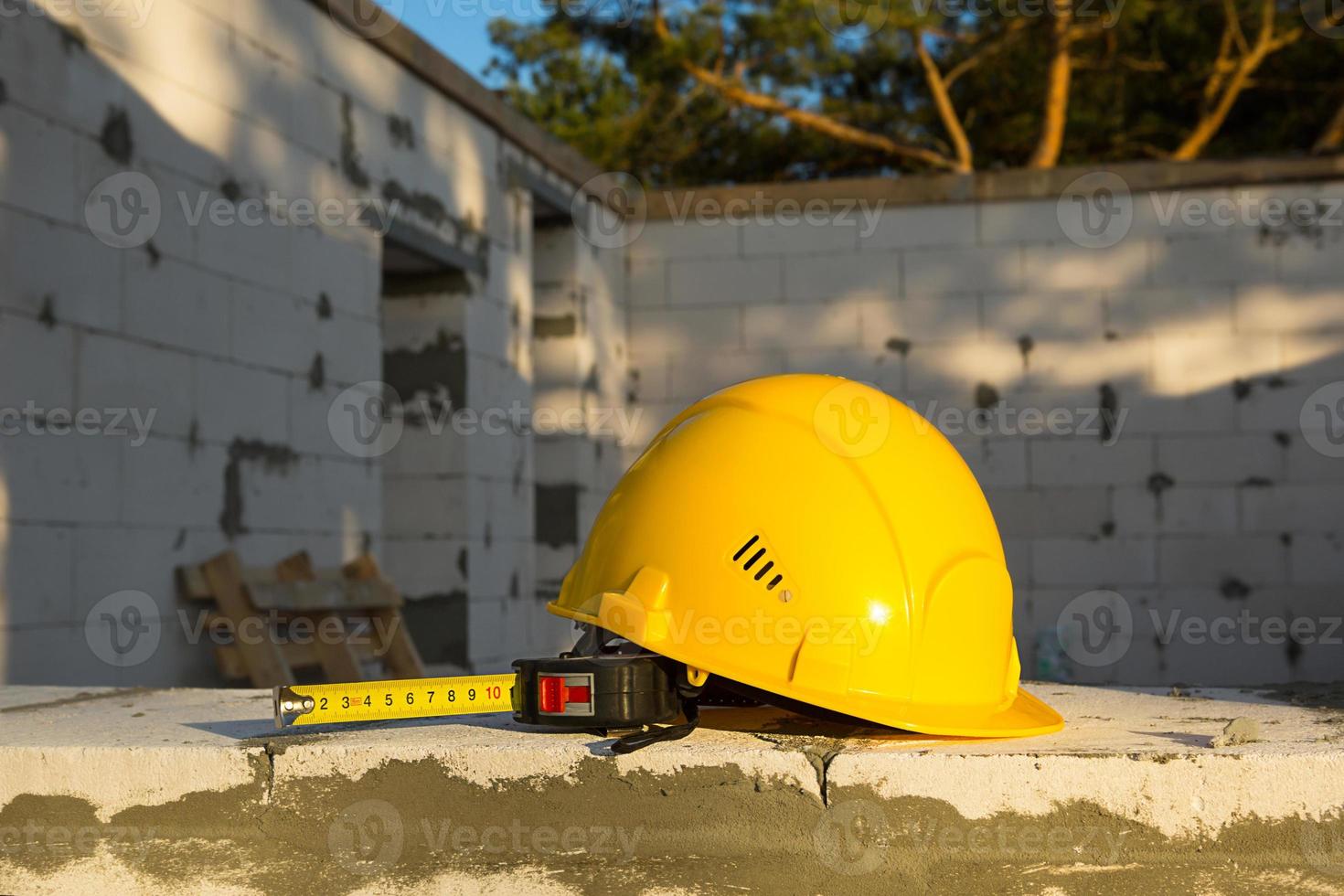Construction hardhat and measuring tape measure on the window of a house under construction made of blocks of porous concrete. Workflow, architecture and engineering, building. Work safety and tools. photo