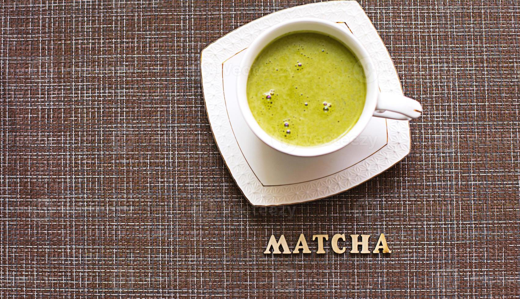 Japanese matcha green tea is poured into a white mug and on a white saucer in powder. Inscription in wooden letters in English. Tea set, invigorating drink, vigor, antioxidant. space for text photo