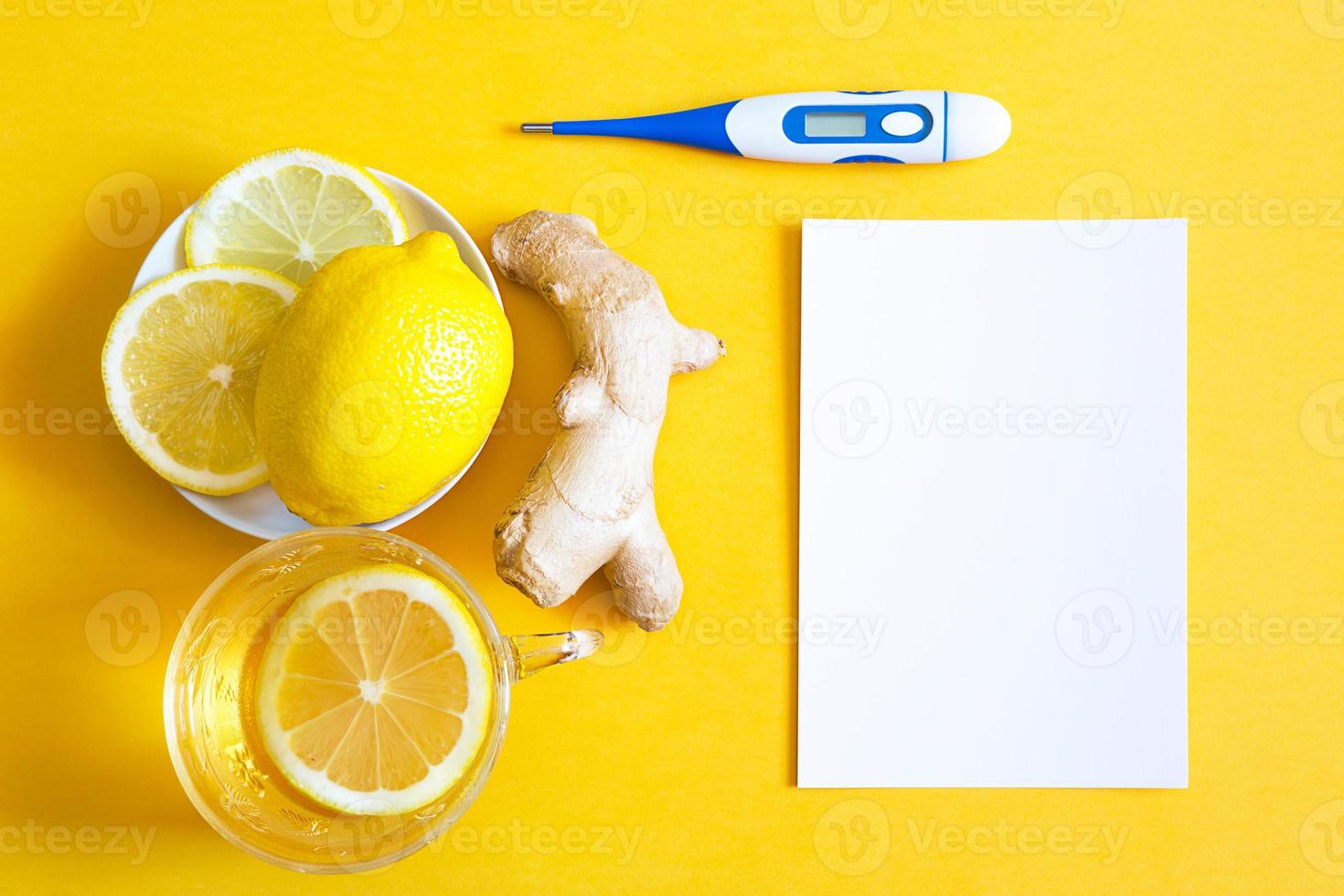 Medicinal tea in a cup, ginger, lemon-strengthen the immune system in the cold season, thermometer and copy space, sheet for notes. Vitamin drink for health and ingredients on yellow background. photo