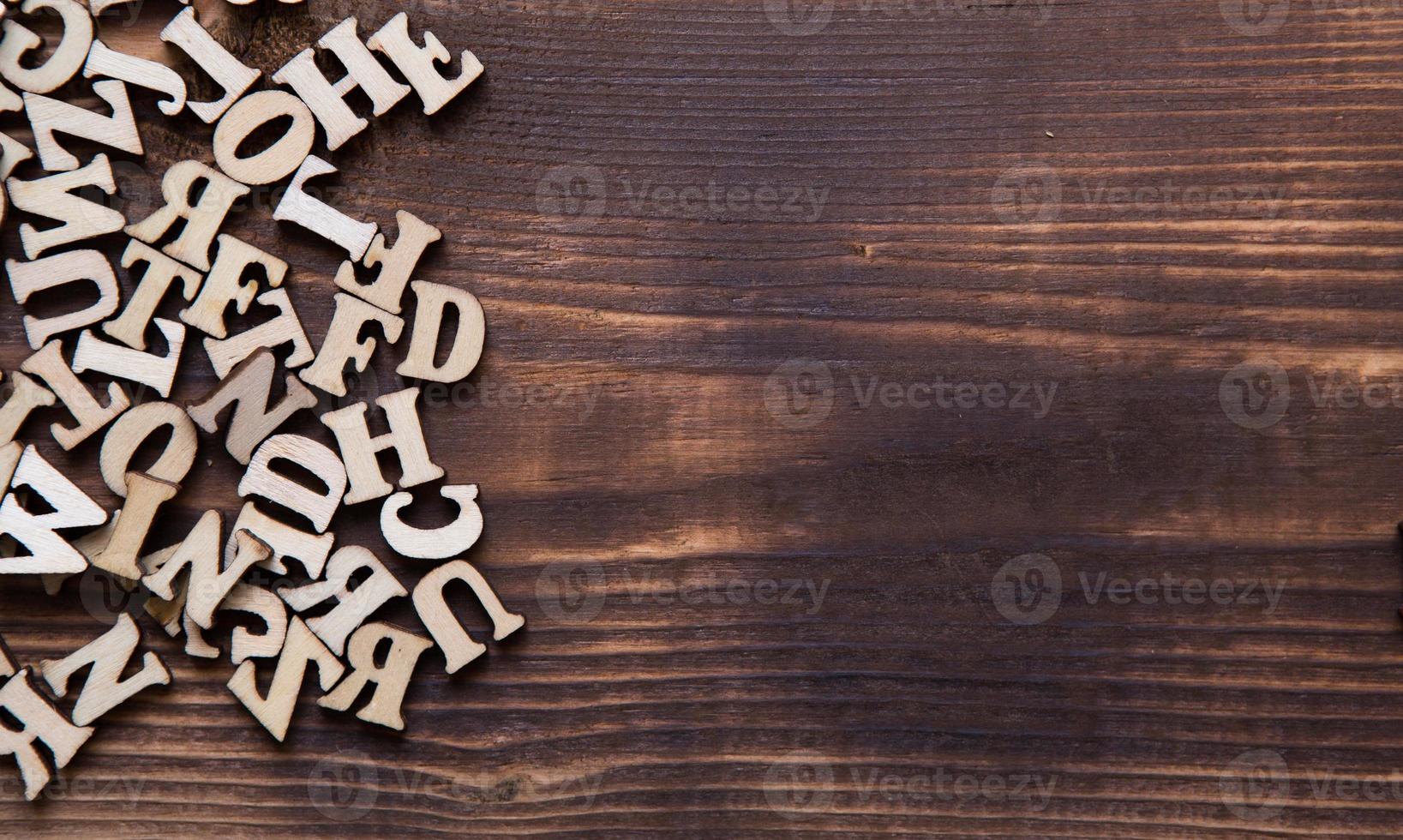 Letters of the English alphabet on a dark wooden background. The concept of education, word games, needlework. Space for text photo