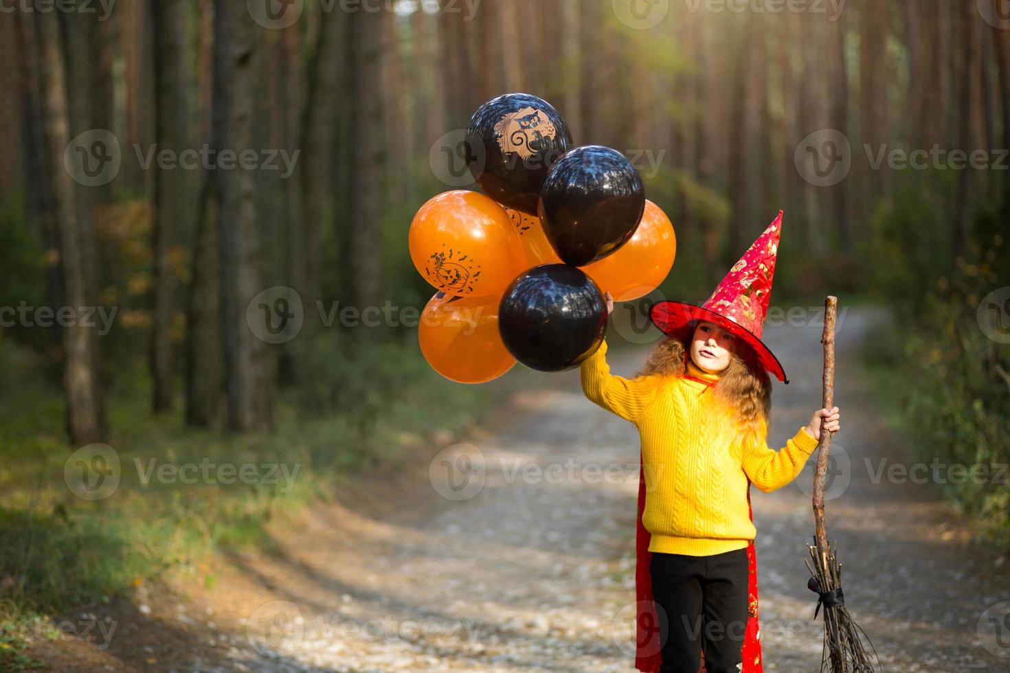 conferencia deberes oferta una niña con un disfraz de bruja y un sombrero en una escoba con globos  naranjas y negros está jugando en el bosque de otoño, yendo a una fiesta de  halloween 7192982