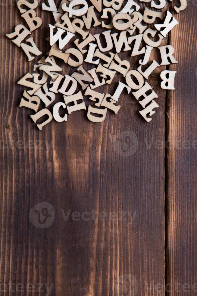 Letters of the English alphabet on a dark wooden background. The concept of education, word games, needlework. Space for text photo