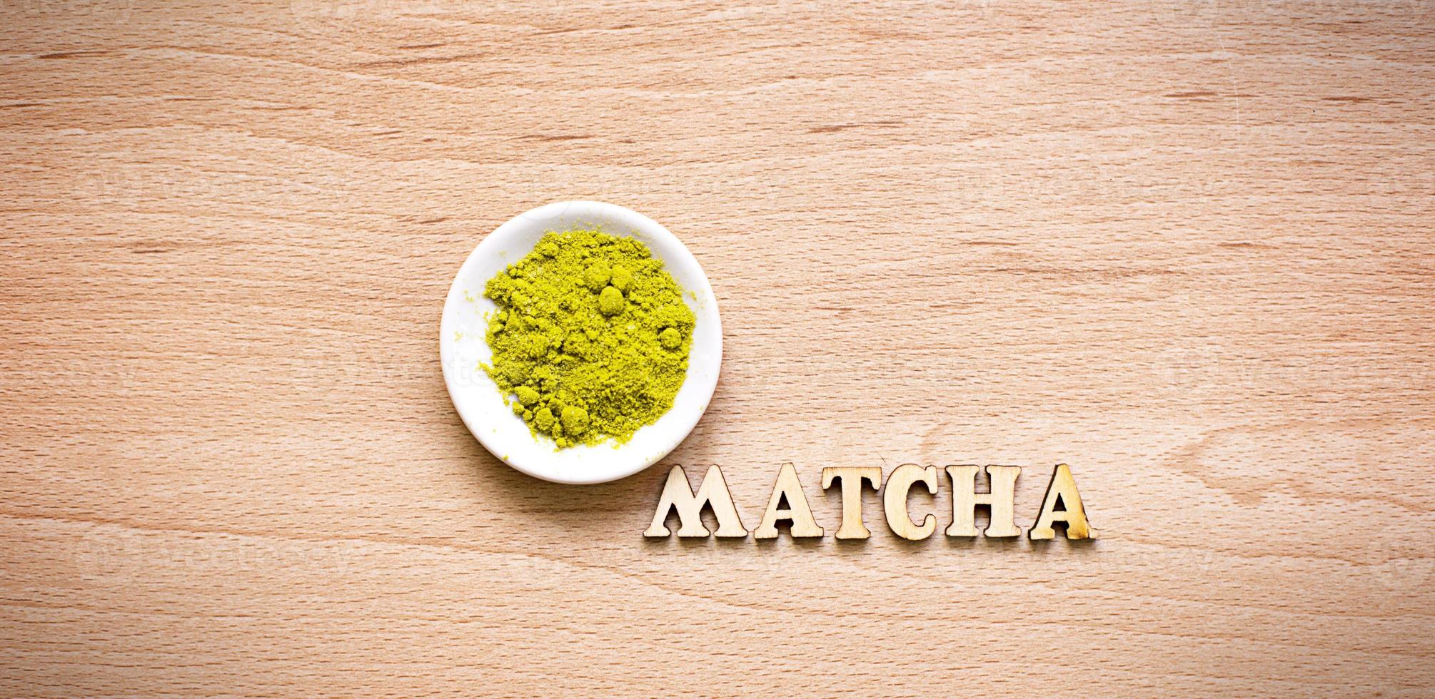 Japanese Green powder matcha tea on a platter, on a brown background. Inscription of the wooden letters in English. Loose powder. Space for text. Cooking, an ingredient for an invigorating drink photo