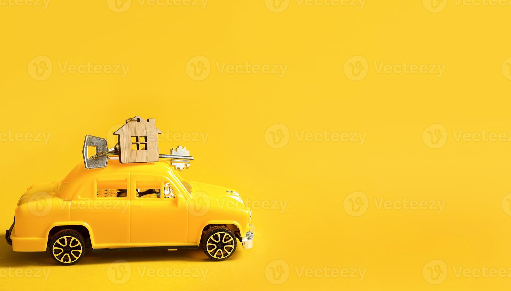 Yellow toy car with a key to the house on the roof on a color background. Moving to a new home, mortgage, buying an apartment, taxi. Copy space. photo