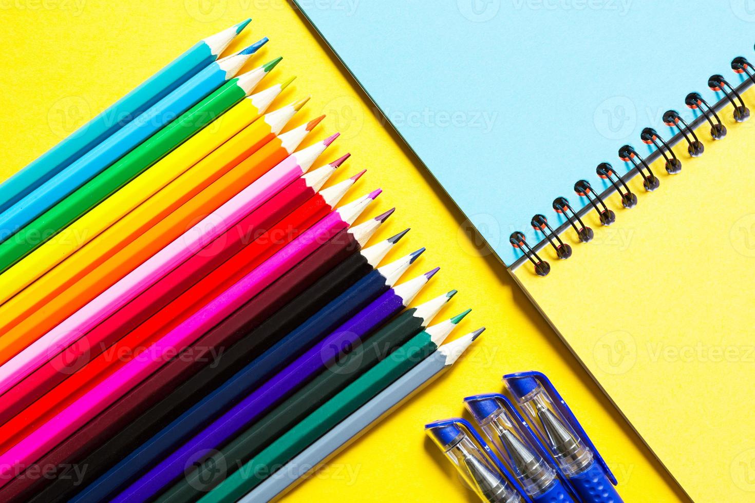 Rainbow palette of colored pencils with a spiral notebook on a yellow background,mock up, flat lay. Back to school, student recruitment, artist, drawing lessons. Copy space. Stationery for creativity photo