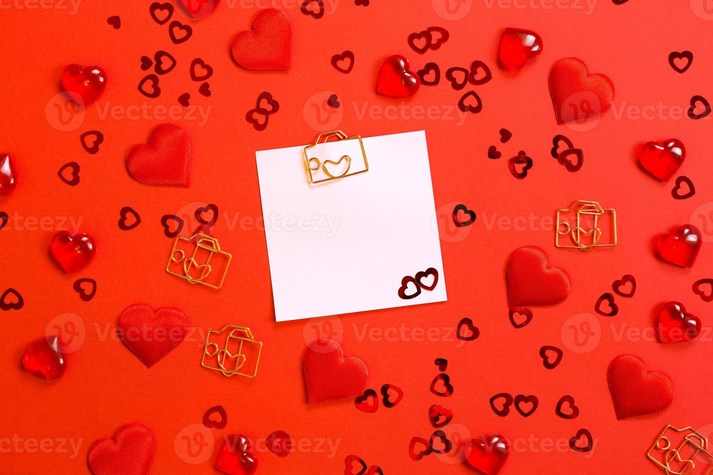 Square sheet for notes with a paper clip in shape of a letter and a heart. Decor of couples in love with hearts on a red background. Valentine's Day, message, greeting, declaration of love. Copy space photo