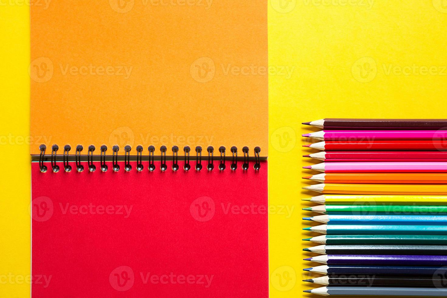 paleta arcoiris de lápices de colores con un cuaderno en espiral sobre un fondo amarillo, maqueta, puesta plana. regreso a la escuela, reclutamiento de estudiantes, artista, lecciones de dibujo. copie el espacio papelería para la creatividad foto