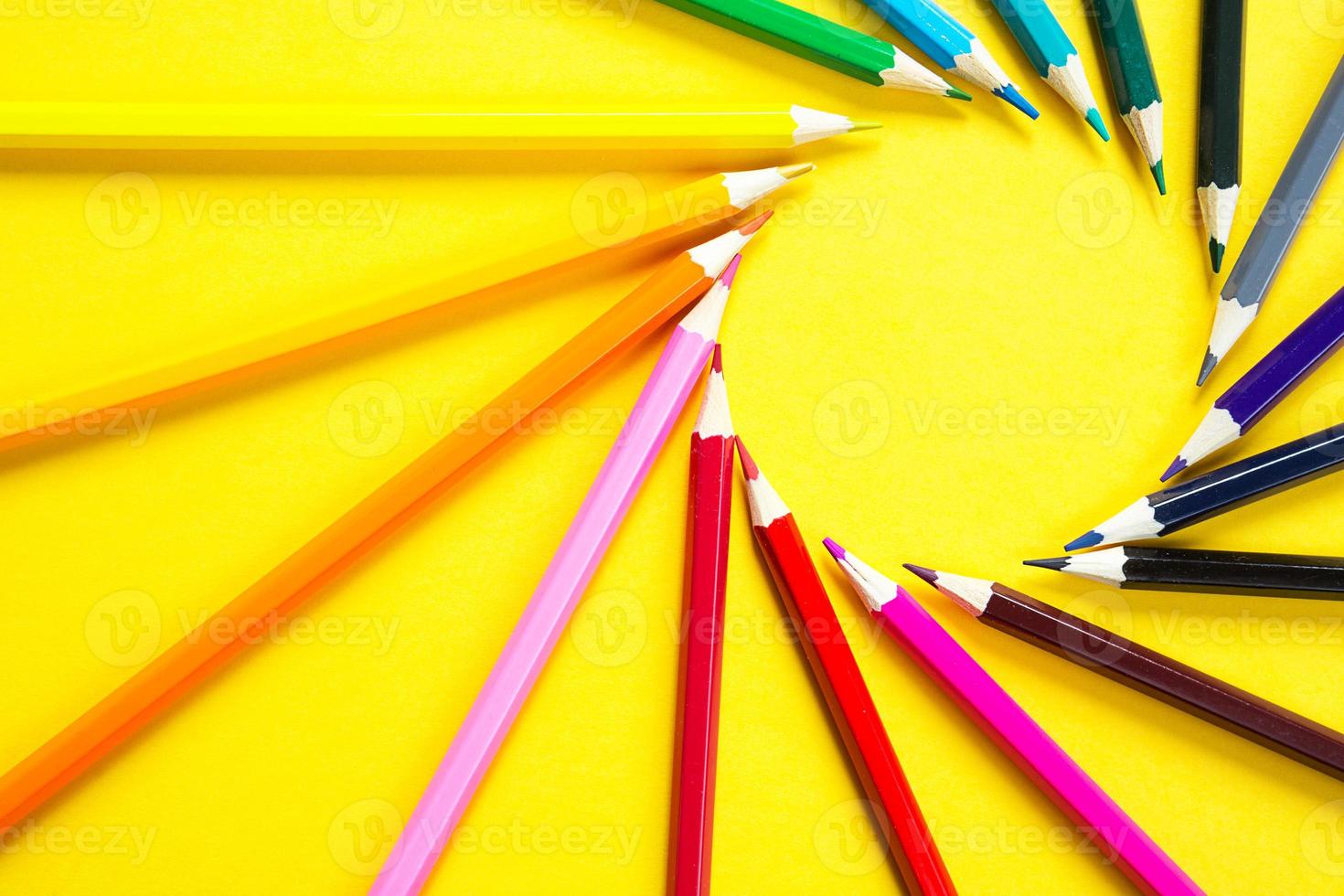 Set of colorful pencils on a yellow background is laid out in a circle in the shape of the sun. Copyspace, frame. Back to school, artist, drawing lessons. Stationery for creativity, draw photo