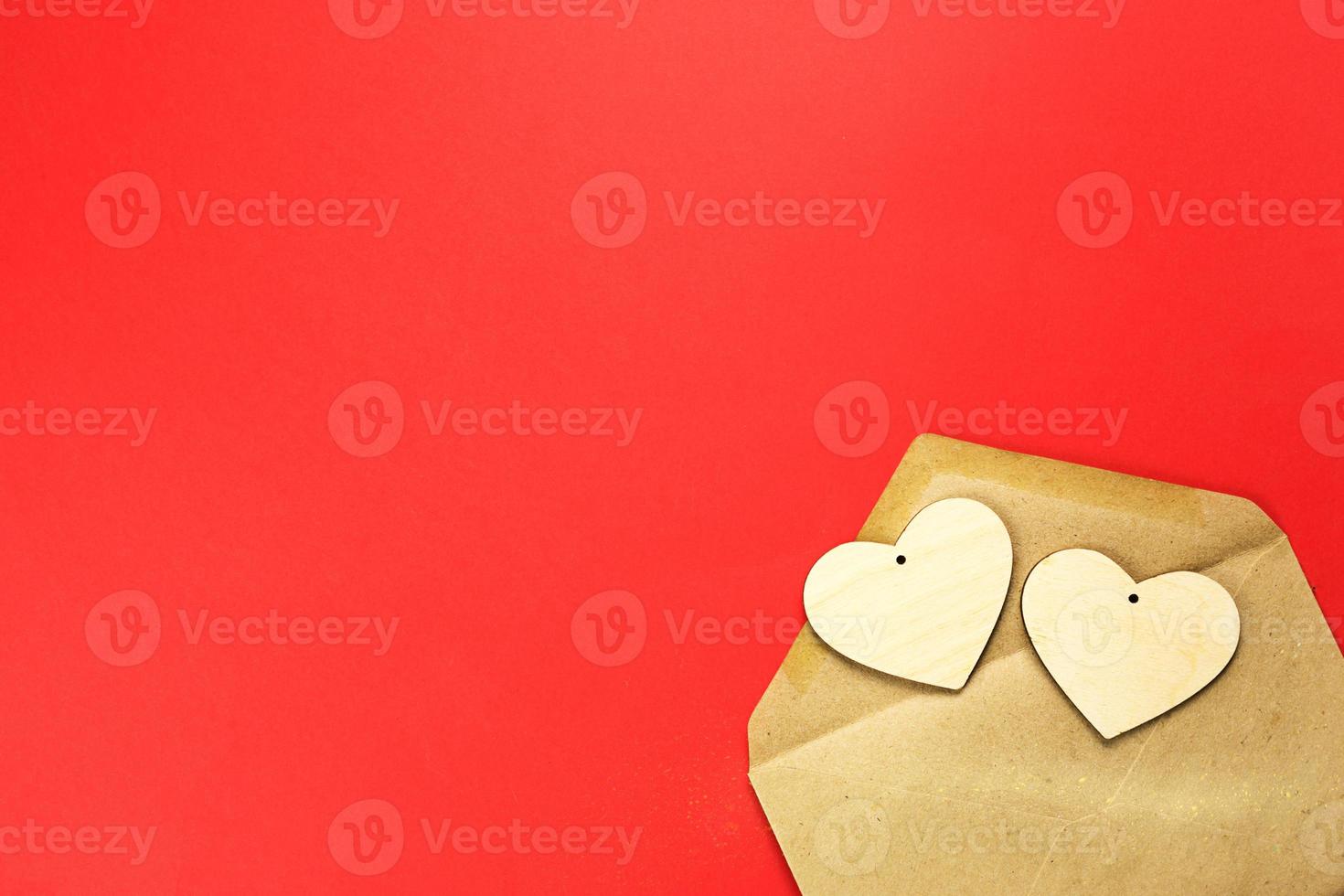 Wooden hearts spill out of an open envelope on a red background. Valentine's Day, love letter, declaration of love, acquaintance. Copy space, mock up photo