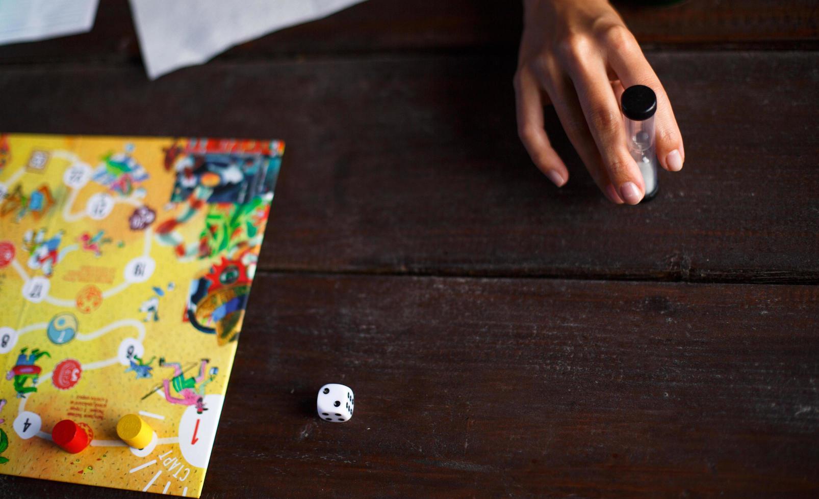 Kaluga, Russia - June 20, 2020. Board game Ekivoki, chips, cube, timer on a table and hands in background. Teamwork, intellectual relaxation, corporate event, playing at home with children. Copy space photo
