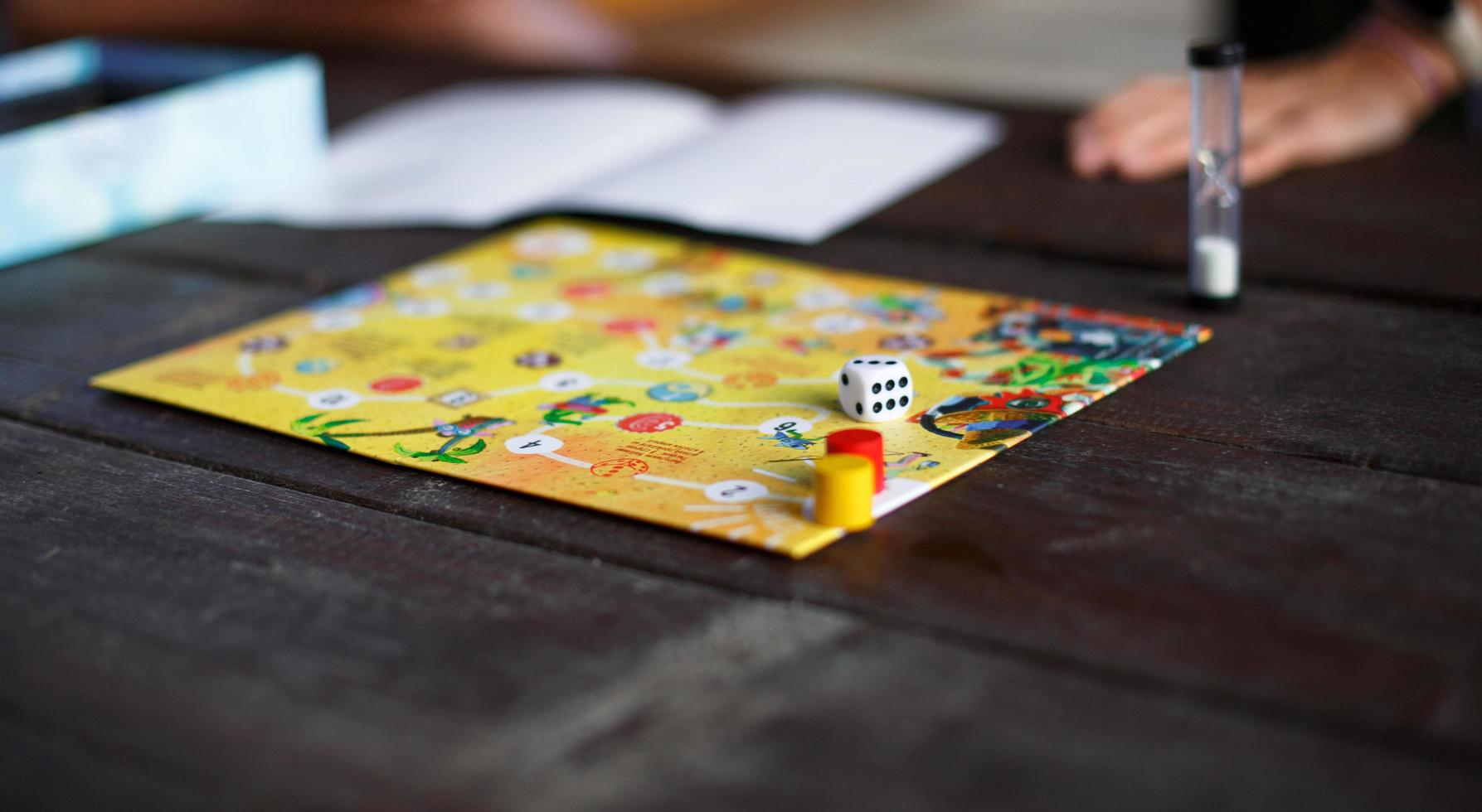 Kaluga, Russia - June 20, 2020. Board game Ekivoki, chips, cube, timer on a table and hands in background. Teamwork, intellectual relaxation, corporate event, playing at home with children. Copy space photo
