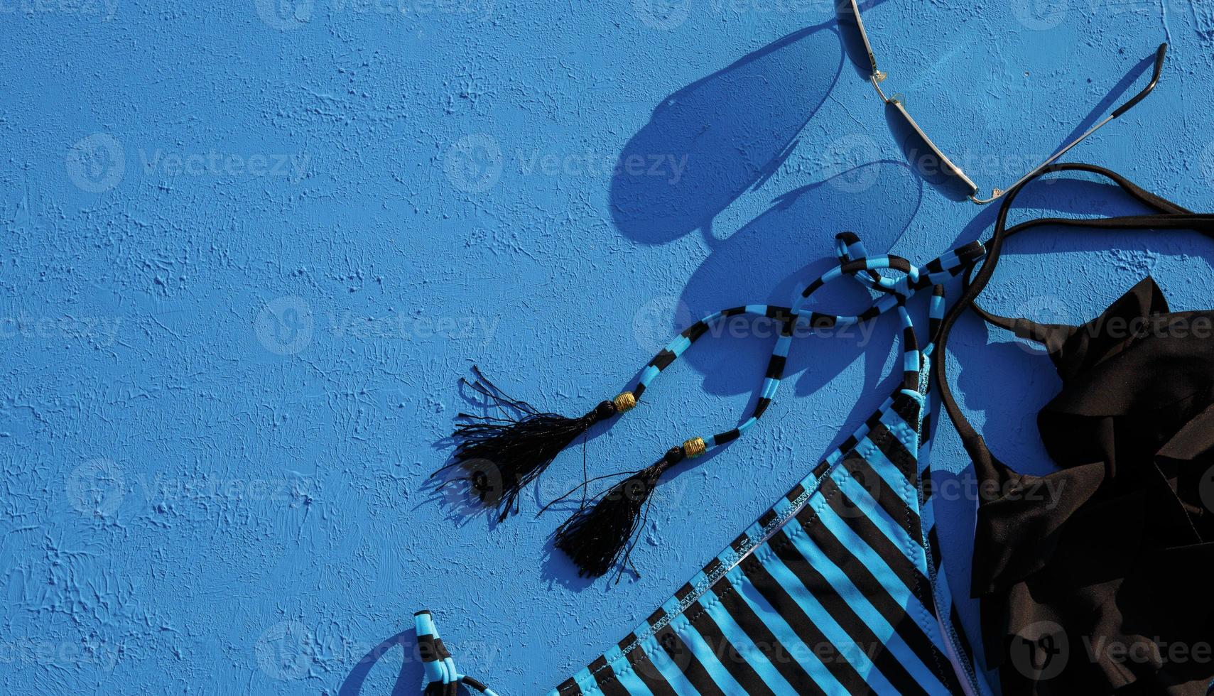 accesorios de mujer para unas vacaciones en la playa sobre un fondo azul. el concepto de viaje al mar, relajación, natación, protección uv, bronceado. Agencia de viajes y turismo. lugar para el texto. marco. plano foto