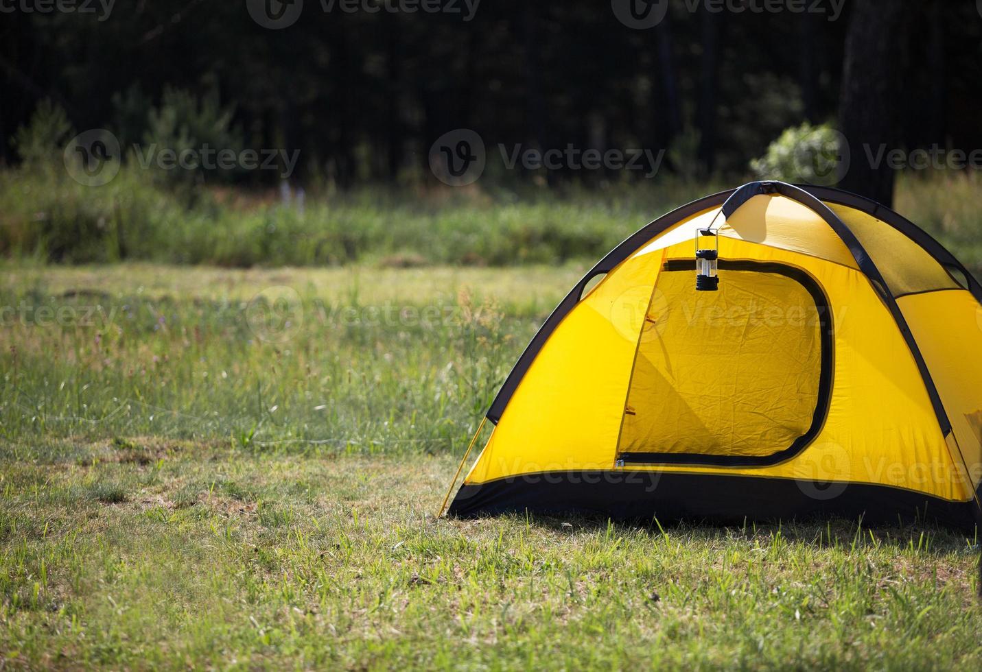 Installed tourist tent and a camping lantern in nature in the forest. Domestic tourism, active summer holidays, family adventures. Ecotourism, social distance. Copy space photo