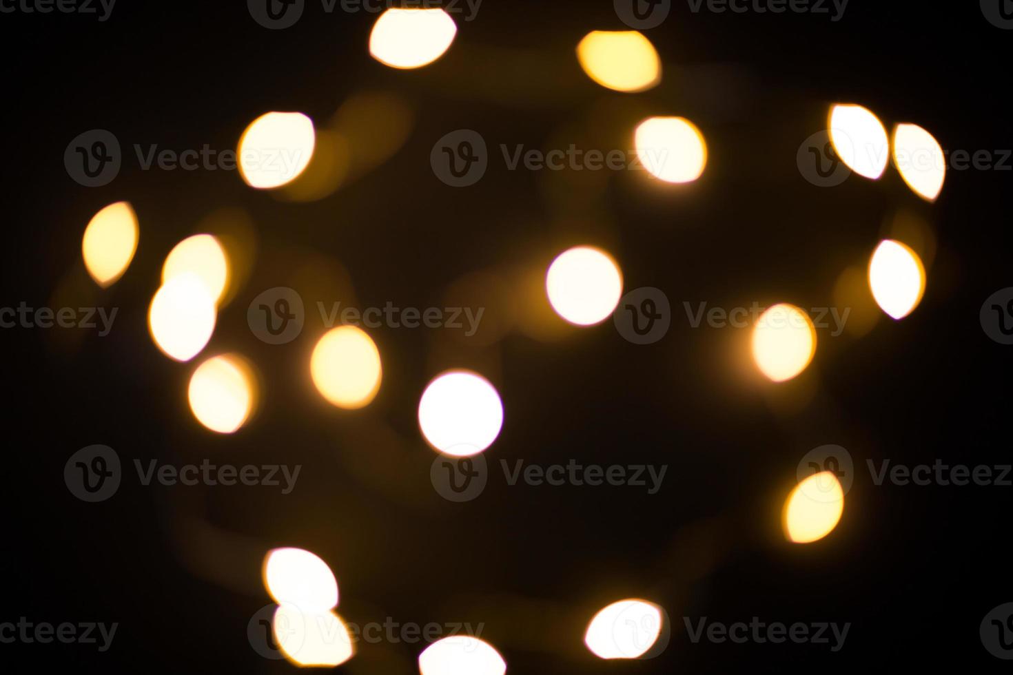 Yellow and gold lights garland in a blur on a black background. Bokeh of flying circles in the defocus. Festive atmosphere of Christmas and new year. Celebrate background photo