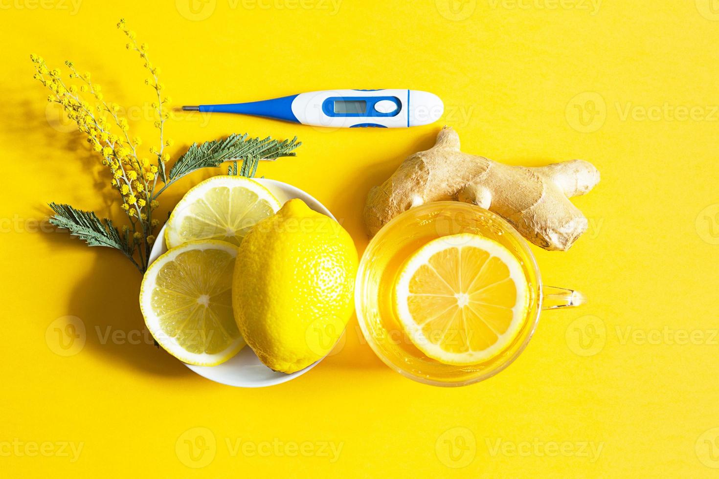 Medicinal tea in a cup, ginger, lemon, acacia-strengthen the immune system in cold season, thermometer  - flatly. Vitamin drink for health and ingredients on yellow background. photo