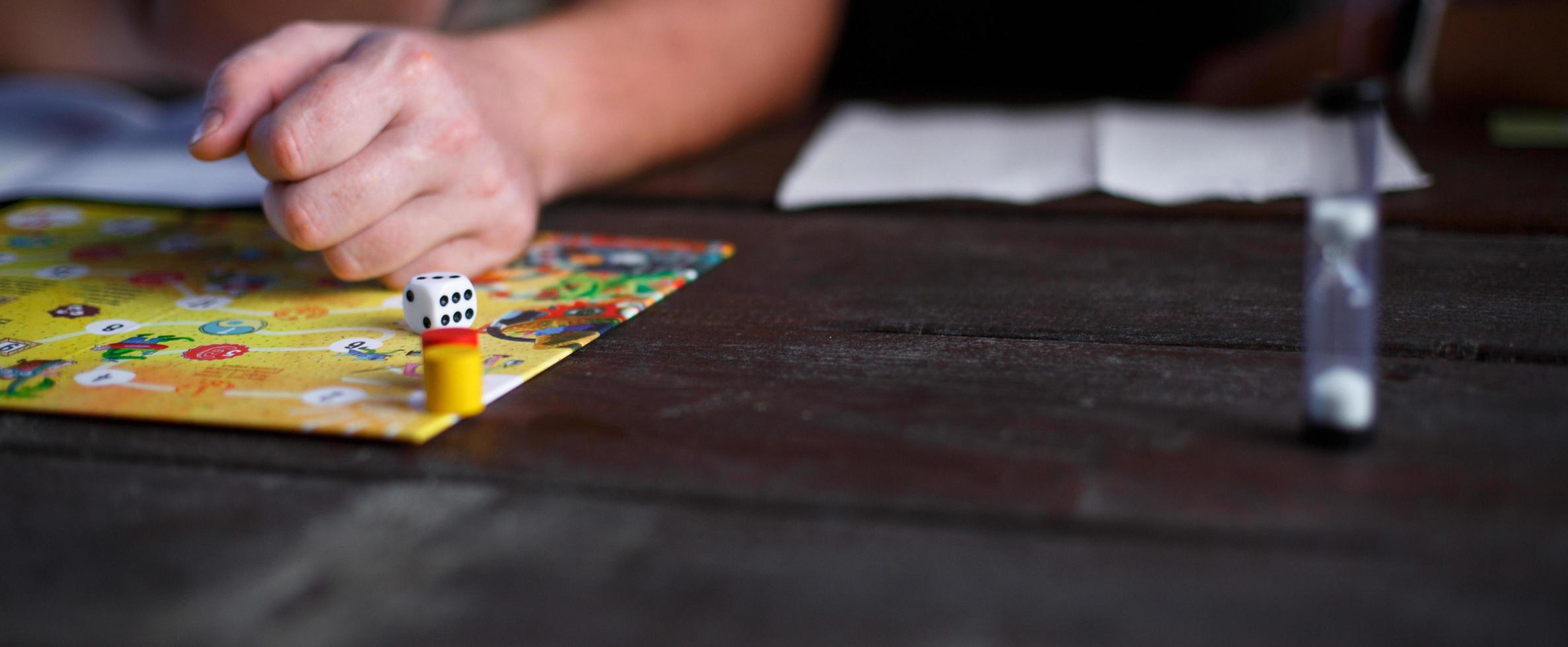 Kaluga, Russia - June 20, 2020. Board game Ekivoki, chips, cube, timer on a table and hands in background. Teamwork, intellectual relaxation, corporate event, playing at home with children. Copy space photo
