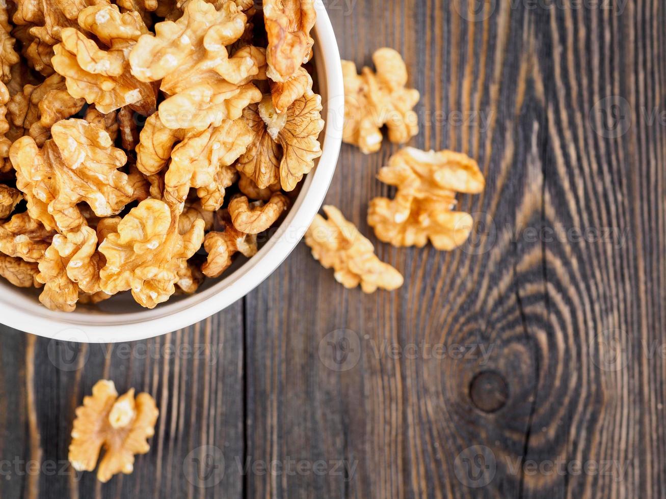 Top view of glass jar with a handful of walnut, circassian nuts on a wooden dark background, selective focus. photo